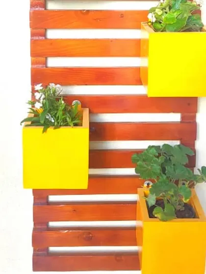 We love using bright colors to make a statement. These vibrant yellow planters are mounted on a wooden pallet-style frame, creating a cheerful and modern piece of wall decor.