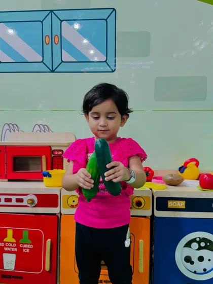 A toddler explores different textures and shapes with our toy vegetables in the pretend kitchen.