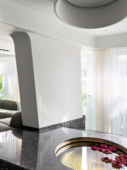 The amphitheater in Apartment 56 is a meditative space designed for reflection and informal conversation. A white teardrop sculpture hovers over a gold-lined reflective pool, bridging art, architecture, and interior design.