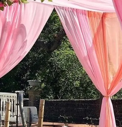 A close-up of a beautifully draped mandap with peach fabric and pastel floral arrangements.