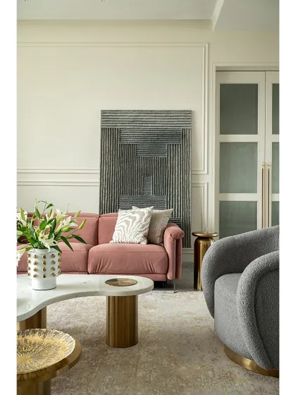 A closer look at the living room in our 2,700 sq.ft. Mumbai apartment. The combination of a plush pink sofa, a textured gray armchair, and brass accents creates a sophisticated and comfortable seating arrangement.