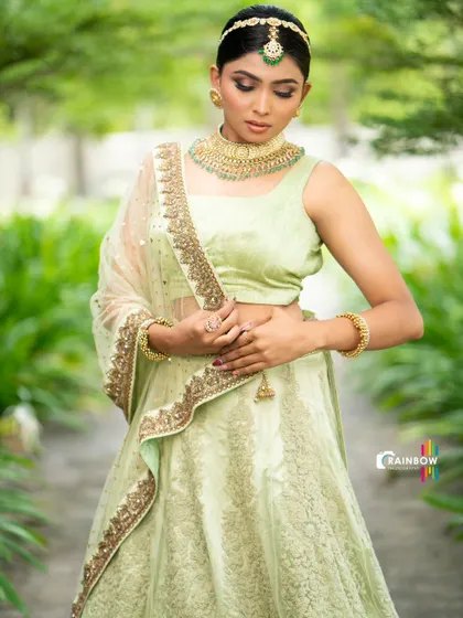 A portrait shot showcasing the pastel green lehenga, styled with a matha patti and choker for a complete, regal look.