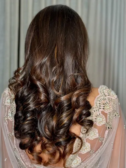 A back view of the client's hair, showing soft, bouncy curls perfect for a reception or party.