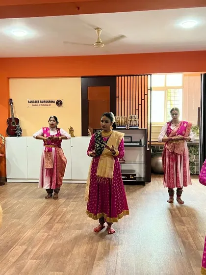 Kathak students in pink costumes performing a piece for the examiners.