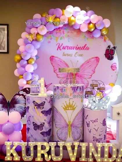 A full view of this elaborate butterfly-themed first birthday, featuring a milestone photo board and custom props.