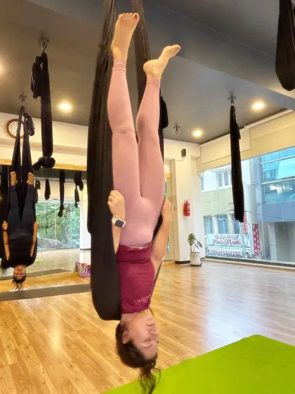 The reflection in the mirror shows another student in the background, highlighting the group setting of our aerial sessions.