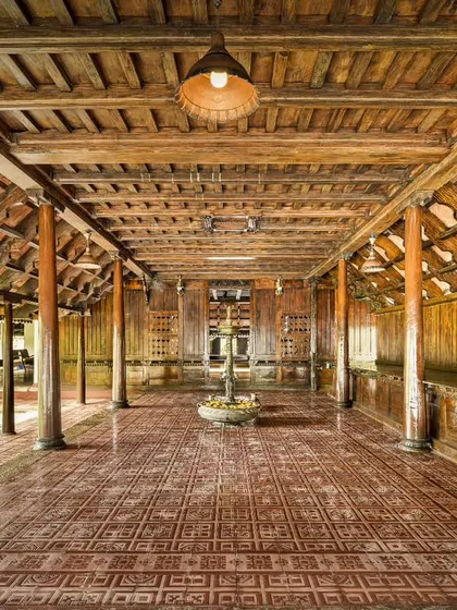 The long, open veranda of a heritage building, showcasing the traditional wooden pillars and tiled roof. This architectural style is designed for natural ventilation and enjoying the surrounding nature.