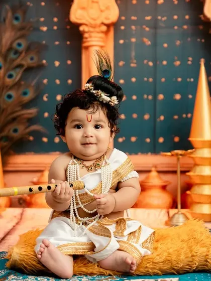 A charming portrait of a baby dressed as Lord Krishna, holding a flute and sitting in a beautifully decorated palace scene.