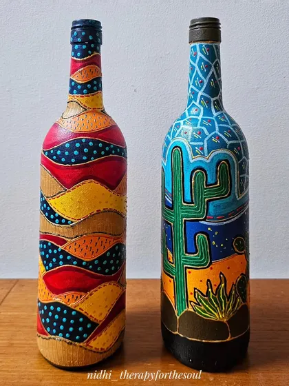 Two of my experimental painted bottles side-by-side: the abstract patchwork design and the desert cactus theme.