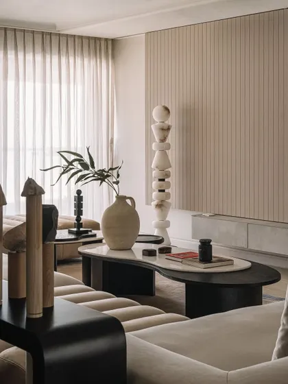 The living room at Kanso House is a canvas of tonal shades, accentuated with wood and black elements. The space is designed for pause and reflection, with curated art and furniture that add character.