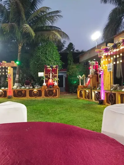 An evening view of an outdoor event space with multiple rustic-themed buffet stations illuminated by string lights.