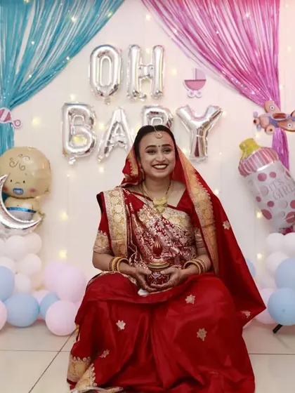 A full view of a happy client at her baby shower. I created a traditional look with a red saree, complete with a radiant makeup base and a classic red lip to celebrate this special day.