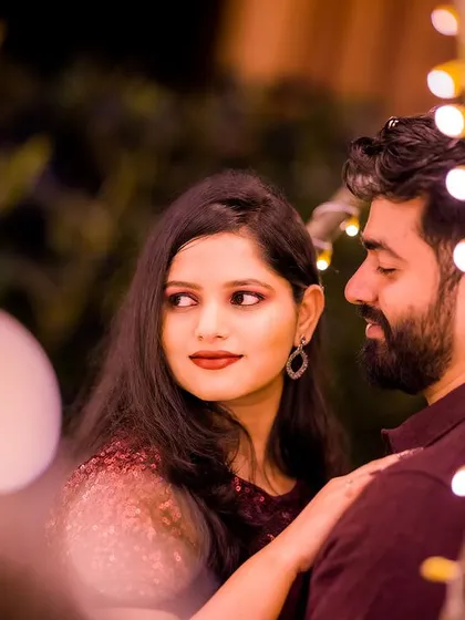 A beautiful close-up portrait using the fairy lights to create a warm, glowing frame. This shot focuses on the stolen glance and the intimate connection between the couple.