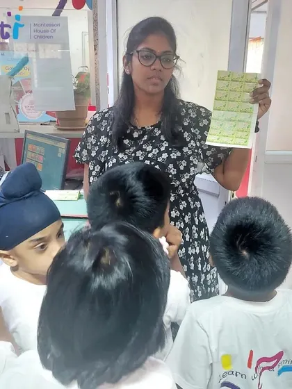 A postal employee shows the children a sheet of stamps, explaining their purpose. The children were fascinated by the different designs and colors.
