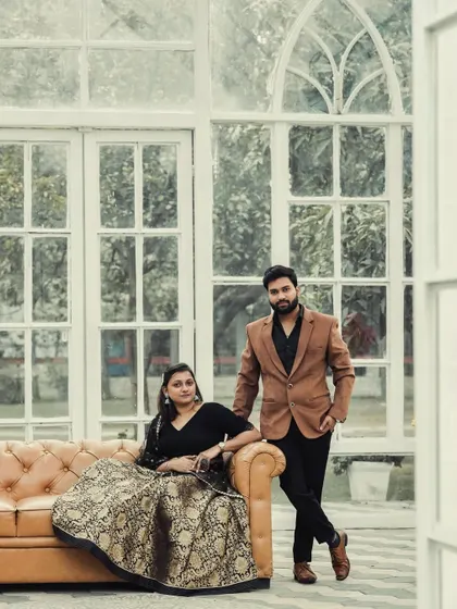 An elegant, posed portrait of the couple in a glasshouse setting, exuding sophistication and style.