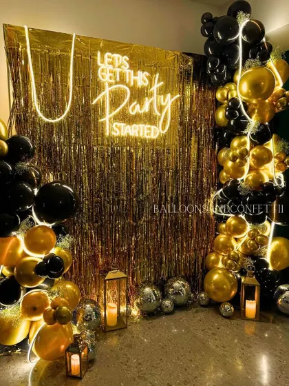 Let's get this party started! A classic black and gold theme gets a modern twist with a gold fringe backdrop, a bold neon sign, and organic balloon arrangements.