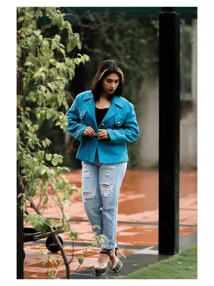 An outdoor fashion shot featuring a bright blue jacket. The model's pose is confident and stylish, creating a modern and urban look.