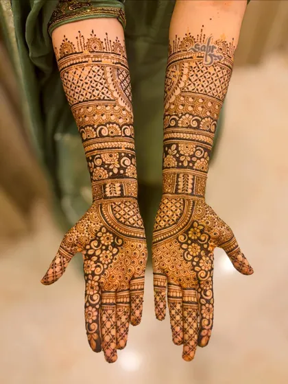 A subtle yet meaningful customization. This beautiful bridal design includes the groom's name, "Sabir," written in elegant script on the upper arm.