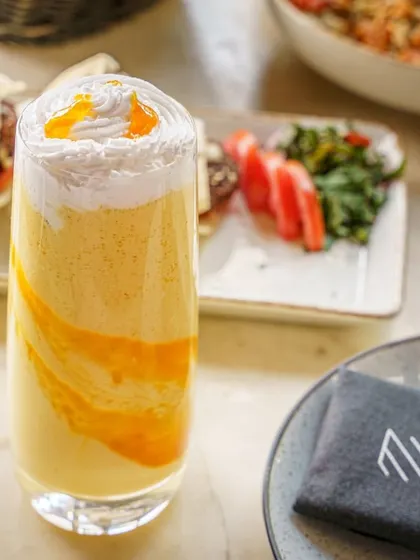 A creamy mango smoothie, beautifully layered in a tall glass. This shot is perfect for cafes and restaurants looking to promote their seasonal drink specials.