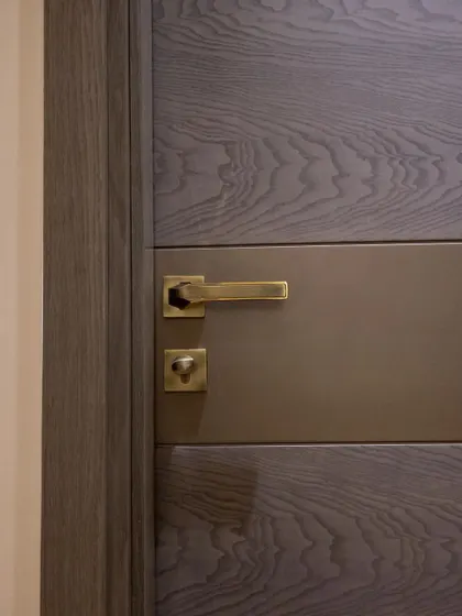 A detail shot of the door handle and lock on the grey wood veneer door, showcasing the quality of the hardware I use.