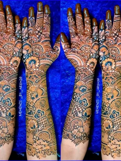A full view of a heavy bridal design against a vibrant blue background. The patterns extend from the fingertips to the mid-forearm for a complete bridal look.