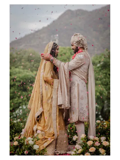 A full-length shot of the couple during their Varmala, set against the lush green hills of Udaipur.