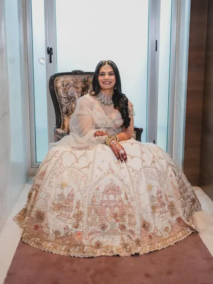 A regal portrait of the bride in her intricately embroidered white lehenga. The soft glam makeup perfectly complements the grandeur of her outfit.
