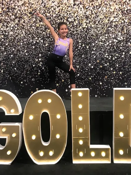 This Xcel Gold athlete strikes a powerful pose, celebrating her success at regionals.