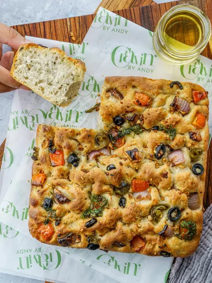 A rustic vegetable focaccia, shot from above. This image highlights the fresh toppings and artisanal quality of the bread, ideal for a bakery's menu.