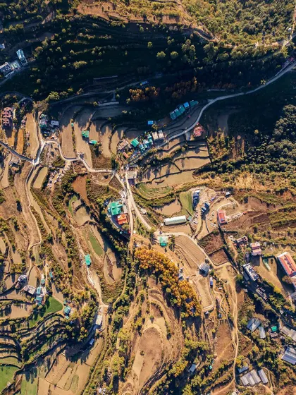 This high-altitude drone photo reveals the terraced farming and winding roads of the hills surrounding Naukuchiatal. It showcases the patterns of human settlement within the vast natural landscape of the Kumaon region.