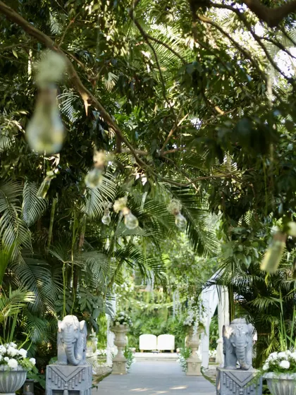 A beautiful view of an elegant white and green wedding aisle, flanked by stone elephant statues.