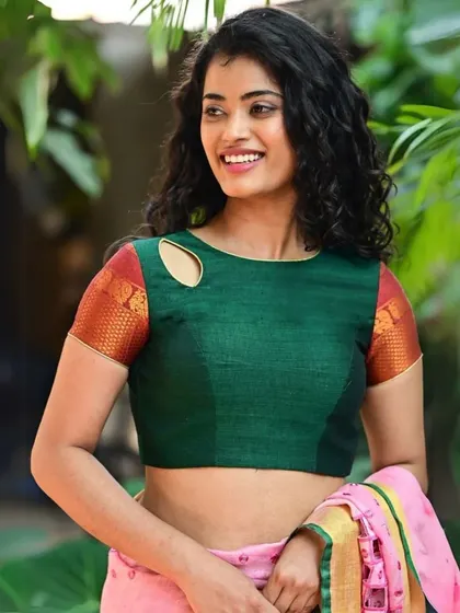 A smiling model wearing our green raw silk blouse with a keyhole cutout on the shoulder.