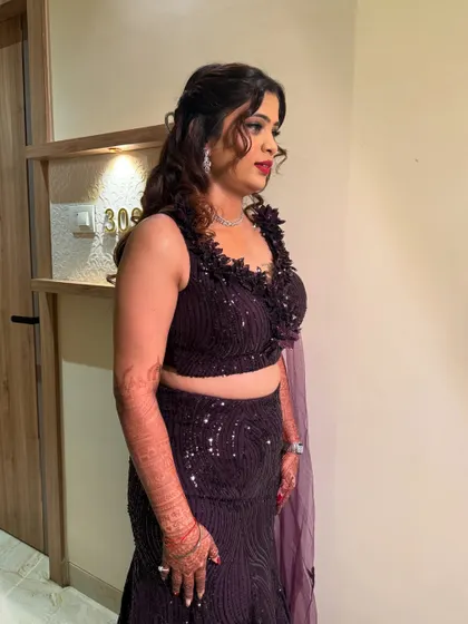A side profile showing the complete sangeet look. The makeup is glamorous yet elegant, and her hair is styled in beautiful waves that complement her outfit.