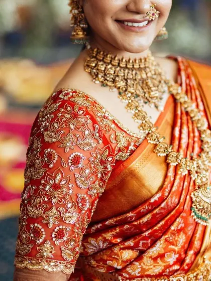 A detailed shot of the intricate zardosi and thread work on the sleeve of the bride's red blouse, showcasing the craftsmanship that goes into each piece.