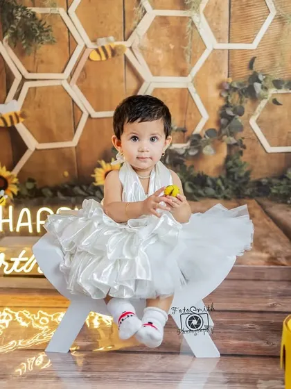 Seated on a little white bench, this birthday girl looks so precious. The details in this bee-themed setup, from the sunflowers to the honey pots, come together to create a truly magical atmosphere.