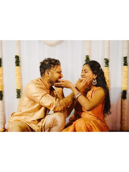 A playful moment where the couple applies Haldi to each other, a gesture of love and fun.
