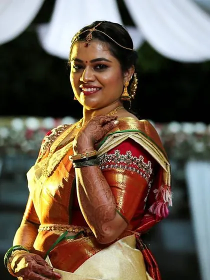 A beautiful throwback to this bride's special day. She is wearing a traditional silk saree with a contrasting red blouse that has detailed embroidery on the sleeves.