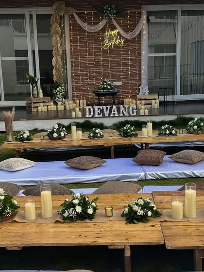 The birthday backdrop for the outdoor movie night, featuring a neon sign, candle lighting, and rustic elements.