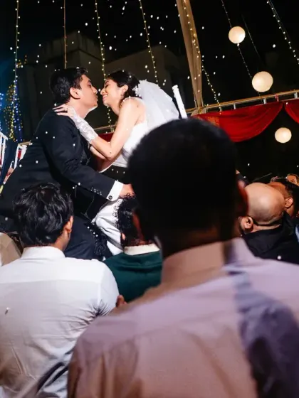 A celebratory kiss on the dance floor, with the couple lifted above the crowd. A perfect shot of reception fun.