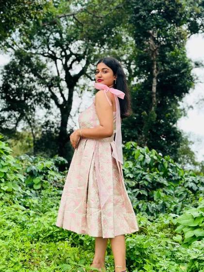 A client looking lovely in a modern brocade dress with pink ribbon ties, perfect for a pre-wedding shoot in a beautiful outdoor setting.
