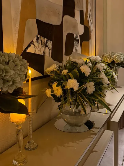 A console table styled with simple white floral arrangements and elegant candle holders. The warm candlelight creates a cozy and inviting atmosphere.
