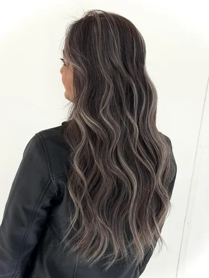 A perfect ash balayage for long, wavy hair. The cool, silvery highlights are expertly blended with the darker base for a dramatic yet sophisticated look.