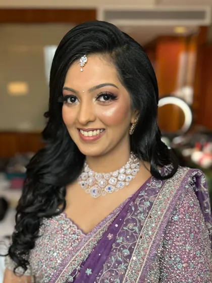A glamorous reception look. This heavily embellished purple saree is draped to perfection, paired with soft curls and sparkling diamond jewelry.
