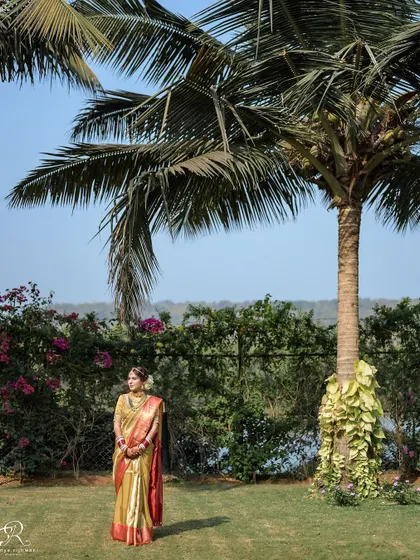 A wide shot of the bride in the beautiful, tropical landscape of her Goa wedding venue.