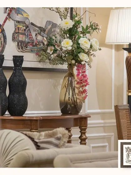 This stunning arrangement of white roses and pink orchids in a tinted glass vase adds a refreshing and elegant touch to this room. The wooden console table enhances the cozy, classic feel.