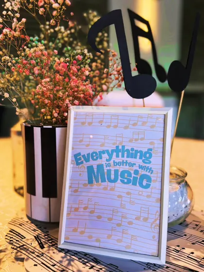 "Everything is better with Music." This framed quote, paired with a piano-key vase and floral arrangement, perfectly captures the spirit of the celebration.