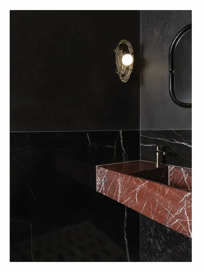 This powder toilet makes a dramatic statement with a monolith basin carved from red marble. The dark charcoal IPS walls and in-situ marble flooring create a dark, enveloping space that feels both luxurious and bold.