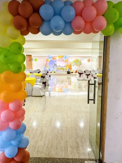 A colorful balloon arch frames the entrance to this party hall, giving guests a preview of the fun and festive 'Winnie the Pooh' theme inside.