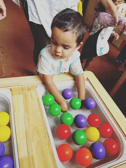 A close-up of a child's hands exploring colorful balls in a water table. This type of focused sensory play is excellent for developing tactile perception and concentration.
