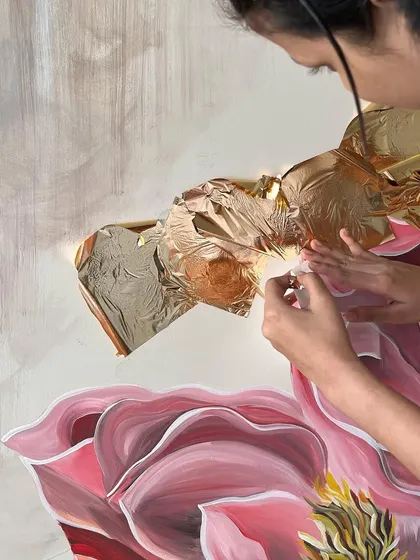 The process of applying rose gold leaf to the 'Native Grace' floral mural. This adds a warm, metallic shimmer that contrasts with the painted petals.